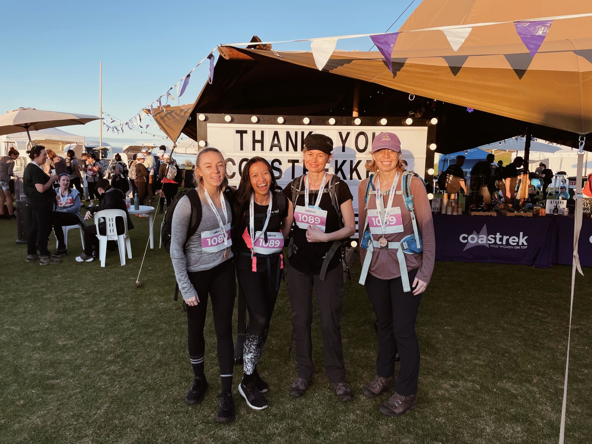 Four women in activewear stand together with medals around their necks