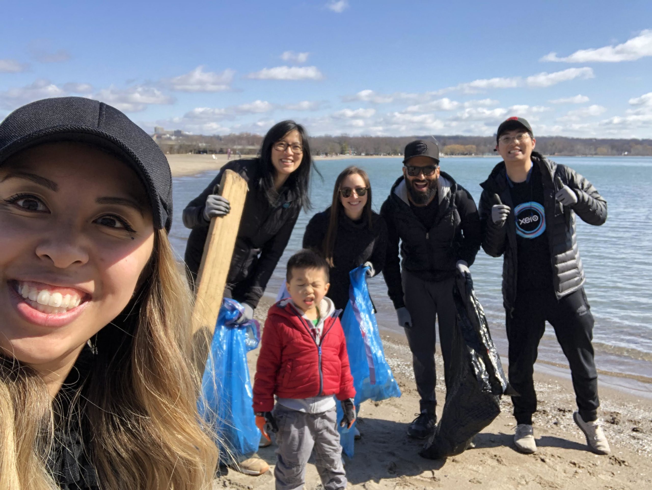 A group of people stand together on a beach with rubbish bags