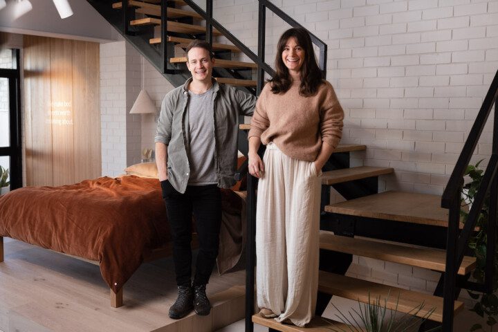 Hayley and Andy Worley standing in front of a staircase near a bed